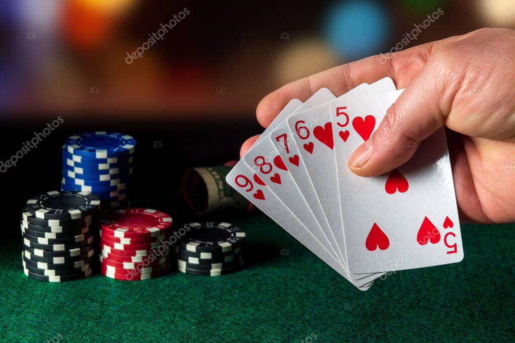 Poker cards with straight flush combination in the game. Close-up of a gambler hand is holding playing cards in poker club. Chips on green table