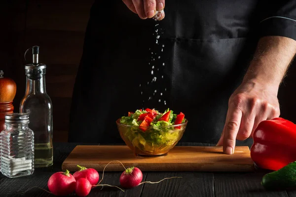 Chef Cook Sprinkles Salt Salad Fresh Vegetables Wooden Table Preparing — Stock Photo, Image