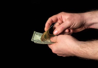 Siyah izole edilmiş arka planda eller dolar sayar. Başarı ve zenginlik fikri. İş ve finans