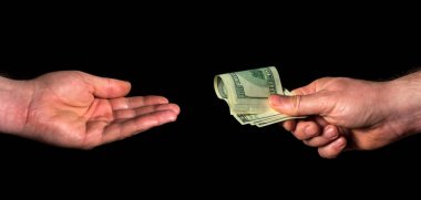 İnsan eli dolar verir ve diğer insan eli siyah izole bir arka plan alır. Rüşvet ve yolsuzluk fikri