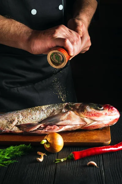 Aşçı ya da şef taze balık kocakafalı sazan balığı serpiştirir. Balık yemi pişirmeye hazırlanıyorum. Restoranda ya da kafe mutfağında çalışma ortamı