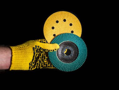 Eldivendeki el, izole edilmiş siyah arka planda aşındırıcı aletler saklar ya da verir. Başarılı bir işe başlama fikri. Ücretsiz reklam alanı.