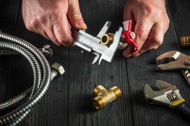 Tesisatçı suyu ya da gaz borusunu bağlamadan önce kalibrenin boyutunu ölçer. Atölyedeki usta tesisatçıya yakın çekim..