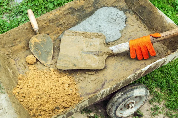 Builder tools and sand and cement for mixing concrete. Preparation for work on the construction site.