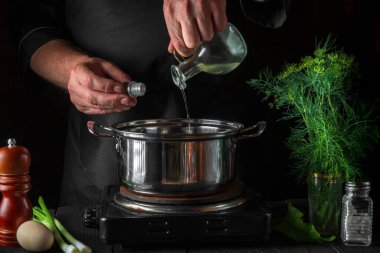 Aşçı börek yaparken tencereye yağ ekler. Restorandaki klasik mutfak masasında çalışma ortamı