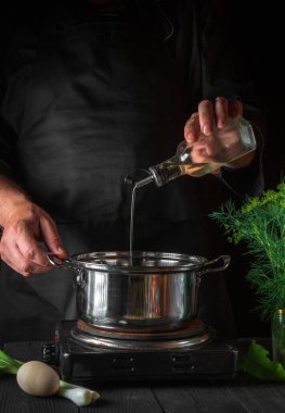 Şef börek yaparken tencereye yağ ekler. Restorandaki klasik mutfak masasında çalışma ortamı. Dikey resim.