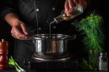 Şef börek yaparken tencereye yağ ekler. Restorandaki klasik mutfak masasında çalışma ortamı