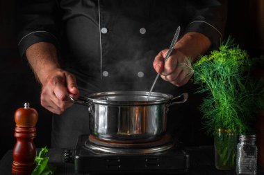 Şef restoranın mutfağında bir tencerede hamur tatlısı hazırlıyor. Yemek pişirirken ellerin yakın plan çekimi..