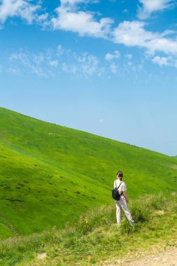Doğada dinlenen sırt çantalı bir gezgin kız. Turist, dağların manzarasına bakar. Dağ güzel manzara 