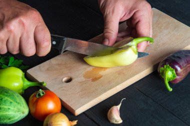 Şefin elleri taze dolmalık biber keser. Restoranın mutfağında salata pişirmek. Salata diyeti için sebze.