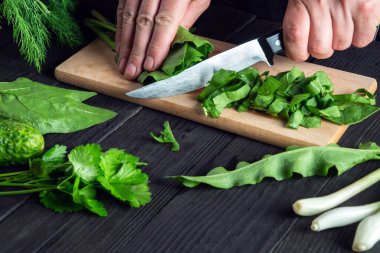 Profesyonel şef bir restoranda ıspanak salatası hazırlıyor. Kesme tahtasında bıçakla sebze kesen bir aşçının elleri.