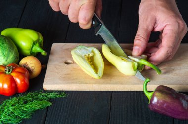 Şef restoran mutfağında salata için dolmalık biber kesiyor. Çalışırken bir aşçının ellerini yakın plan çek.