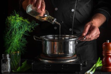 Profesyonel şef börek yaparken tencereye yağ ekliyor. Restorandaki klasik mutfak masasında çalışma ortamı