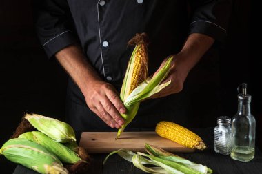 Şef pişirmeden önce olgun mısırı kabuğundan soyar. Restoranın mutfağında çalışma ortamı. Çalışırken aşçının elleri....