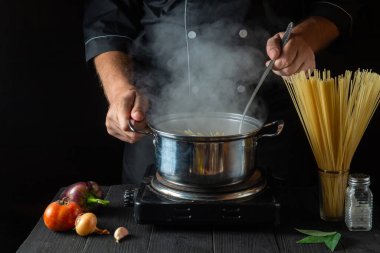 Şef, sebzeli bir tencerede İtalyan makarnası hazırlıyor. Lokanta mutfağında yemek pişirirken ellerinizi yakın plan çekin. Ücretsiz reklam alanı