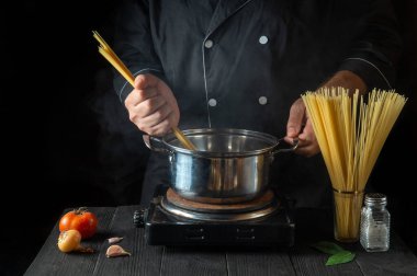 Şef, sebzeli bir tencerede İtalyan makarnası hazırlıyor. Lokanta mutfağında yemek pişirirken ellerinizi yakın plan çekin. Ücretsiz reklam alanı