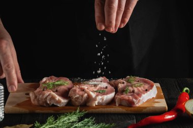 Profesyonel şef ete tuz serpiyor. Pişirmeden önce et hazırlıyorum. Bir restoranın mutfağında çalışma ortamı