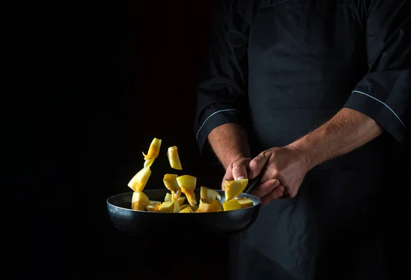Chef prepares zucchini in a pan. Cooking vegetables healthy vegetarian food and meal on a dark background. Free advertising space.