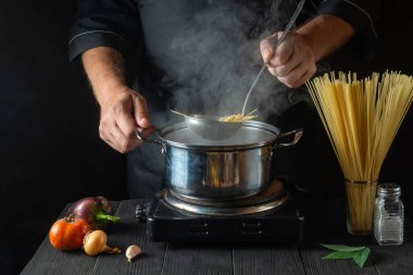 Şef, sebzeli bir tencerede İtalyan makarnası hazırlıyor. Lokanta mutfağında yemek pişirirken ellerinizi yakın plan çekin. Ücretsiz reklam alanı