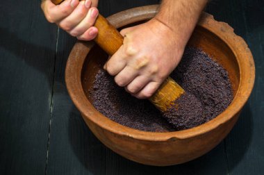 Grinding poppy seeds in an old clay pot for making kutya or pies. The national dish is prepared before any holiday clipart