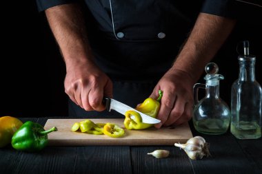 Şef restoran mutfağında salata için dolmalık biber kesiyor. Çalışırken aşçı ellerinin yakın çekimi. Bedava reklam spa 'sı