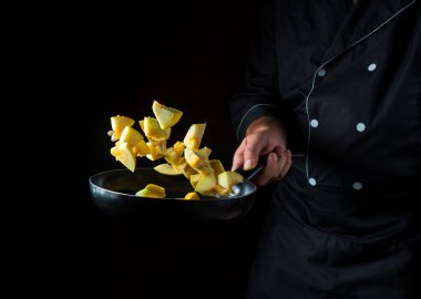 Şef kabağı tavaya koyuyor. Sebze pişirmek sağlıklı vejetaryen yemeği ve yemeği karanlık bir arka planda pişirmek. Ücretsiz reklam alanı.