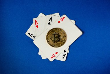 Several playing cards showing aces are arranged with a shiny bitcoin coin in the middle, set on a vibrant blue background, capturing the intersection of gaming and digital currency.