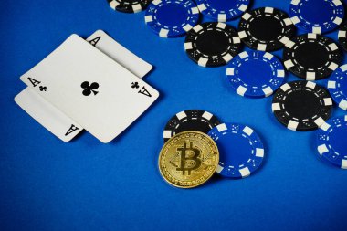 Two playing cards show an ace of clubs next to blue and black poker chips, along with a gold bitcoin coin on a bright blue surface, highlighting a unique gambling scene.