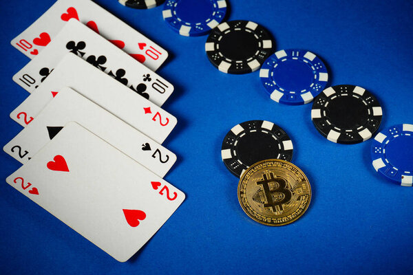 Poker with full house or full boat cards and colorful chips. Bitcoin adds a modern twist to the traditional blue table game.
