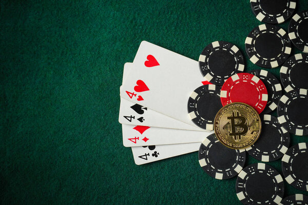 A poker composition with four playing cards of different suits surrounded by black and red casino chips and a bitcoin on green felt.