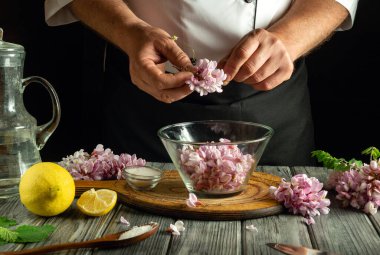 Bir şef taze çiçeklerin yapraklarını dikkatlice çıkarır ve onları bir yemek için hazırlar. Çevreleyen malzemeler arasında limon, tuz ve otlar, pişirme sürecinin geliştirilmesi,.