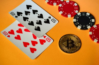Tek bir çifti içeren kartlar, turuncu bir yüzeyde poker çipleri ve Bitcoin 'in yanına yerleştiriliyor ve eğlenceli bir akşam için mükemmel bir oyun sahnesi yaratıyor..
