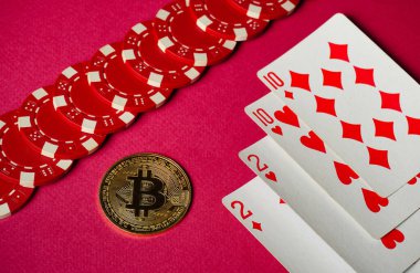 Kırmızı kumar fişleri ve içinde kalpler ve elmasların olduğu iskambil kağıtları parlak pembe bir yüzeye uzanır, Bitcoin 'in yanında heyecan verici bir oyun ortamı yaratır..