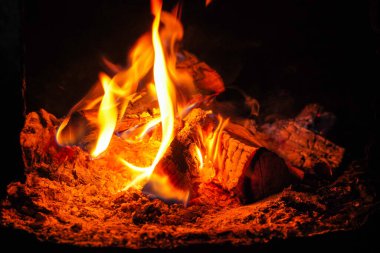 Şöminede yanan odunlardan parlak alevler yükseliyor, odayı sıcaklık ve yumuşak bir parıltıyla dolduruyor. Bu sahne serin bir gecede huzur veriyor..