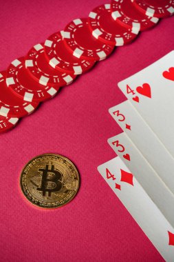 Kırmızı çipler ve Bitcoin ile çevrili iki çift iskambil kağıdından kazanan bir el. Atmosfer beklenti ve rekabetçi ruhlarla dolu..