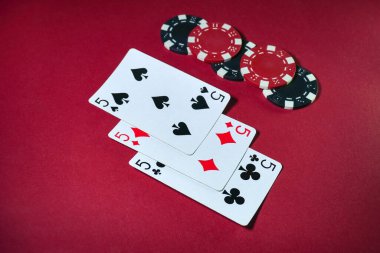 Heyecan verici bir kart oyunu. Kırmızı arkaplanda üç ya da üç tane renkli poker fişi var..