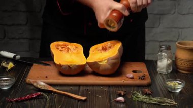 Bir şef taze kabağı ikiye bölerek ve baharatlarla tatlandırarak hazırlar. Köy mutfağında ahşap yüzeyler ve bitkiler var. Sıcak bir atmosfer yaratıyorlar..