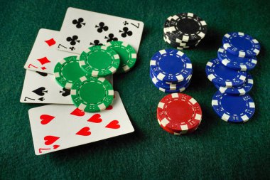 Renkli poker fişleri, yeşil bir keçeli kalem yüzeyinin yanında oturur ve arkadaşlar arasında eğlenceli bir oyun gecesi için canlı bir atmosfer yaratır. Oyuncular strateji geliştirirken heyecan havayı dolduruyor.