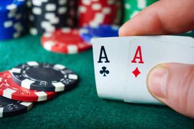Bir oyuncu yeşil keçeyle kaplı bir kumarhane masasında renkli poker fişleri ile çevrili otururken iki as tutuyor. Oyun açıldıkça gerilim havayı dolduruyor..