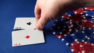 Poker oynarken mavi yüzeyde oynayan bir oyuncu. Kırmızı ve mavi fişler kartların yanına istiflenmiş. Sahne oyunu ve oyuncunun elini gösteriyor..