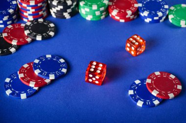 Bir iskambil oyunu. Kırmızı zarlar renkli çiplerin arasındadır. Atmosfer hareketli ve oyuncular birlikte vakit geçiriyorlar..