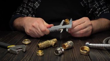 Bir tesisatçı kalibreli tüfeği alır ve ahşap bir masanın üzerindeki pirinçleri ölçer. Çeşitli tesisat parçaları etrafa saçılmış. Sahne gün içinde bir atölyede geçiyor..