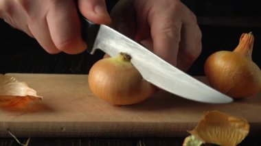 Ahşap kesme tahtasının üzerinde keskin bir bıçakla soğan doğrayan usta bir şef mutfak düzeninde aşçılık hazırlığı ve malzeme işleme sürecini gösteriyor.