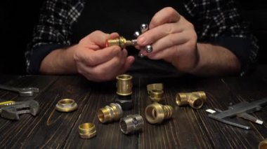 Yetenekli teknisyen, etkili tesisat çözümleri için ahşap bir çalışma yüzeyinde çeşitli araçlar kullanırken pirinç tesisat montajı üzerine odaklanır, bileşenleri hassasiyetle birleştirir.