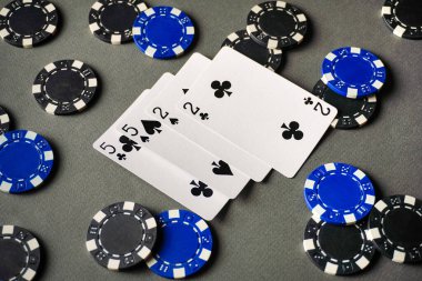 Masada iki çift iskambil kağıdı var. Kartların etrafına mavi ve siyah poker fişleri yerleştirilir. Oyuncular oyuna dahil olabilir.