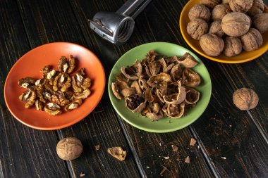 Üç tabakta ceviz ve kabukları ve tahta bir masada duran fındıkkıran var. Sahne, gündüz vakti mutfakta fındık hazırlamayı gösteriyor..
