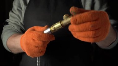 Turuncu eldivenli eller bir metal konnektör ve hortumu manipüle ederek, bir atölye ortamında adım adım montaj sürecini araçlar ve ekipmanlarla gösteriyor.
