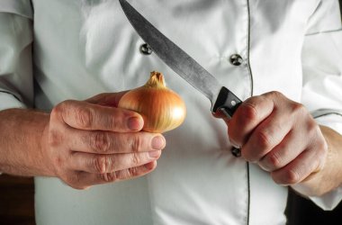 Öğle yemeği için sebze yemeği pişiriyorum. Bir aşçının elinde bir yay ve bıçak..