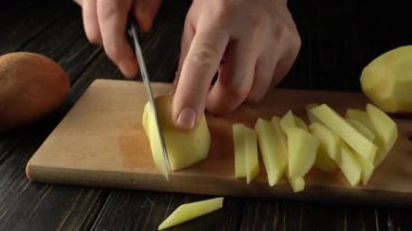 Patates kızartması için ahşap bir kesme tahtasının üzerinde taze patatesleri ince ince dilimlerken görülmüş. Yanında da birkaç patates varmış. Mutfak atmosferi yaratıyormuş..