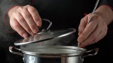 Siyah üniformalı şef tavanın kapağını kaldırıyor, kepçeyle makarna karıştırıyor, restoran mutfağında buhar yükseliyor..